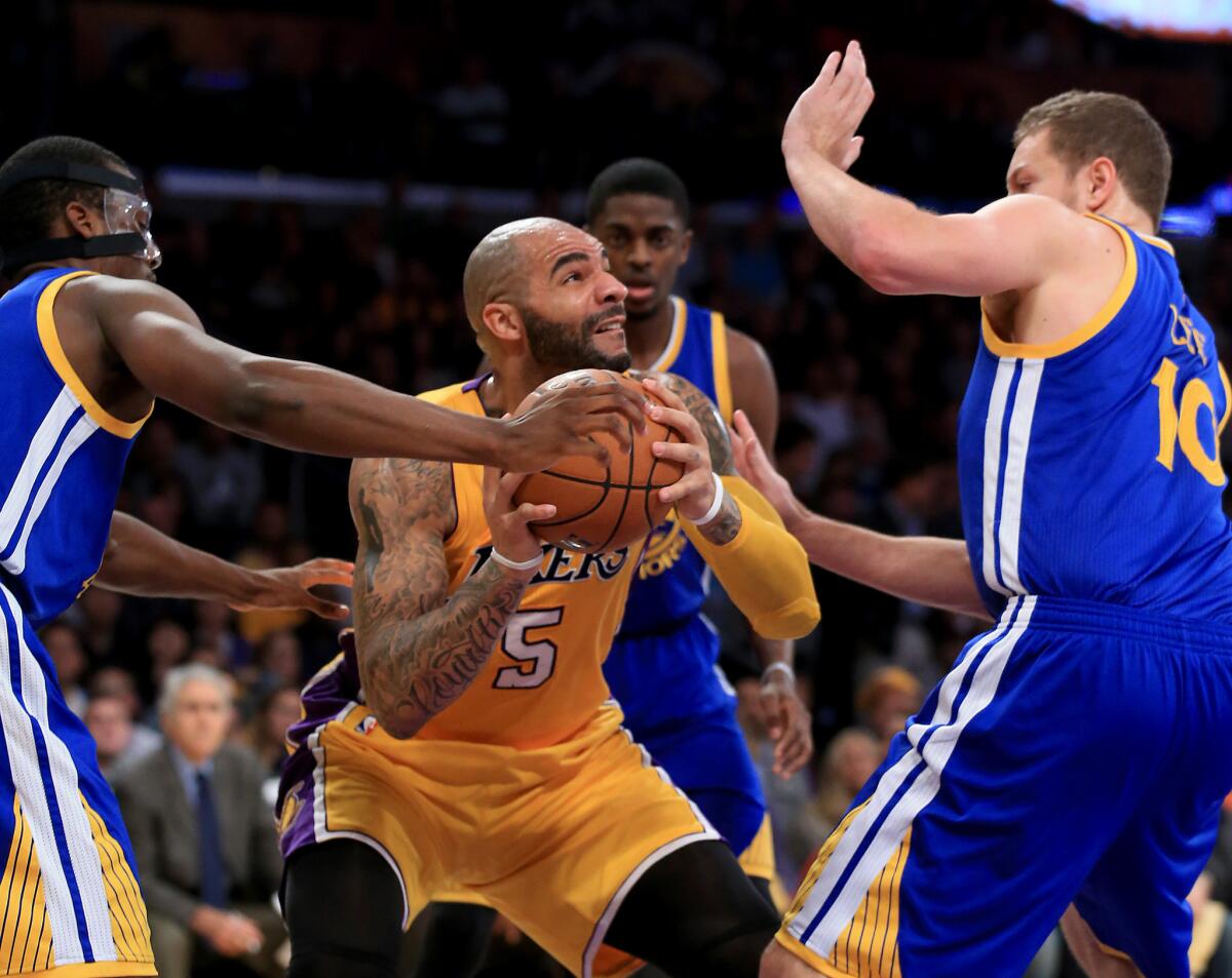 Carlos Boozer draws a crowd of Golden State defenders during the first quarter of the Lakers' 115-105 win over the Warriors.