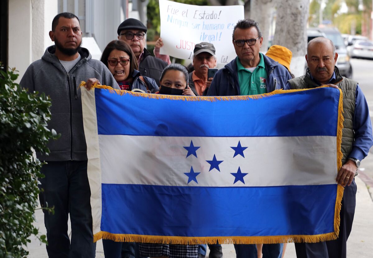 A small group of people hold the Honduran flag during a demonstration.