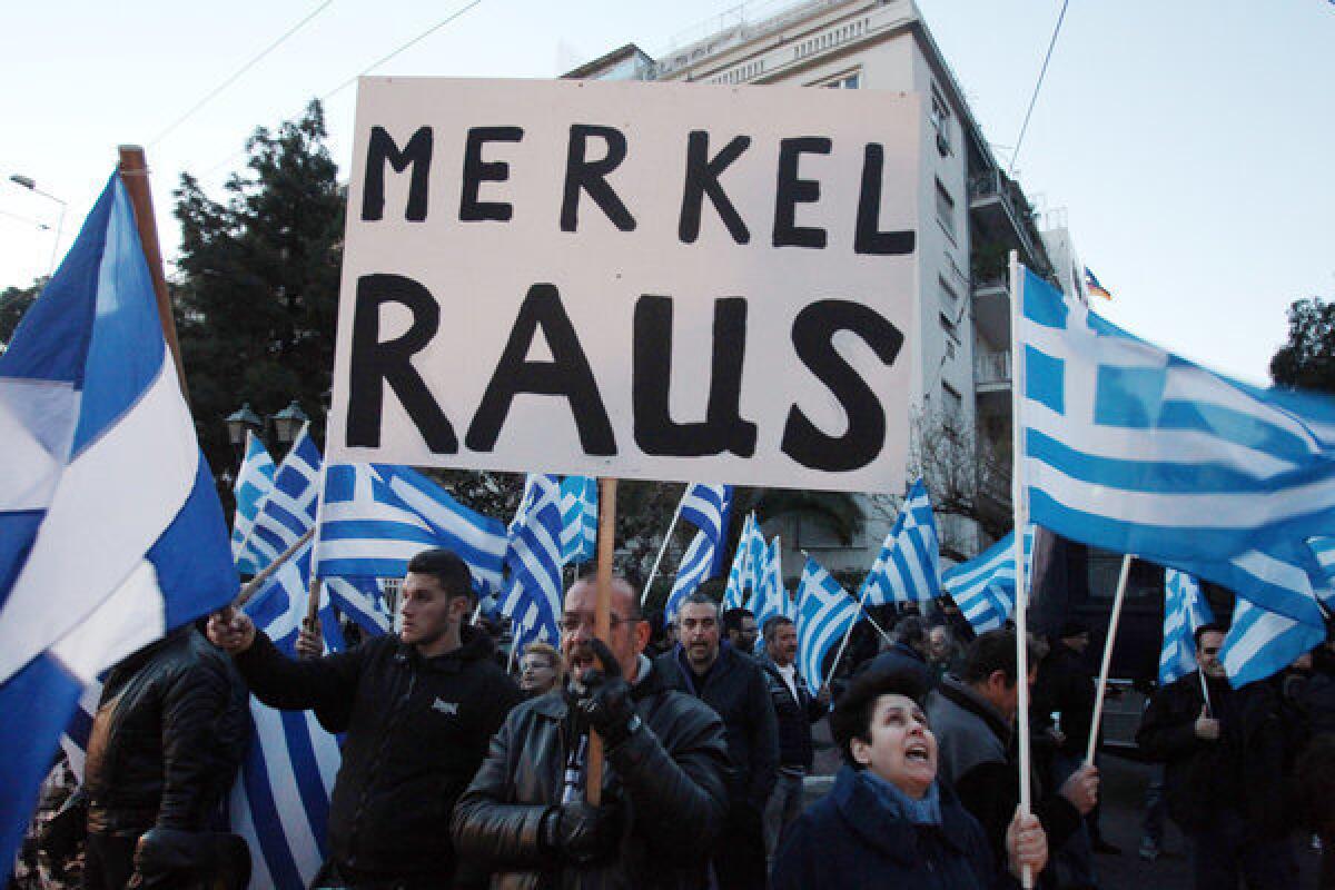 Supporters of the far-right party Golden Dawn hold up Greek flags and a sign that reads in German "Merkel get out" during a protest outside the Germany embassy in Athens.