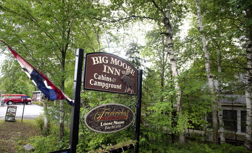 The sign for Big Moose Inn in Millinocket, Maine, is set among trees.