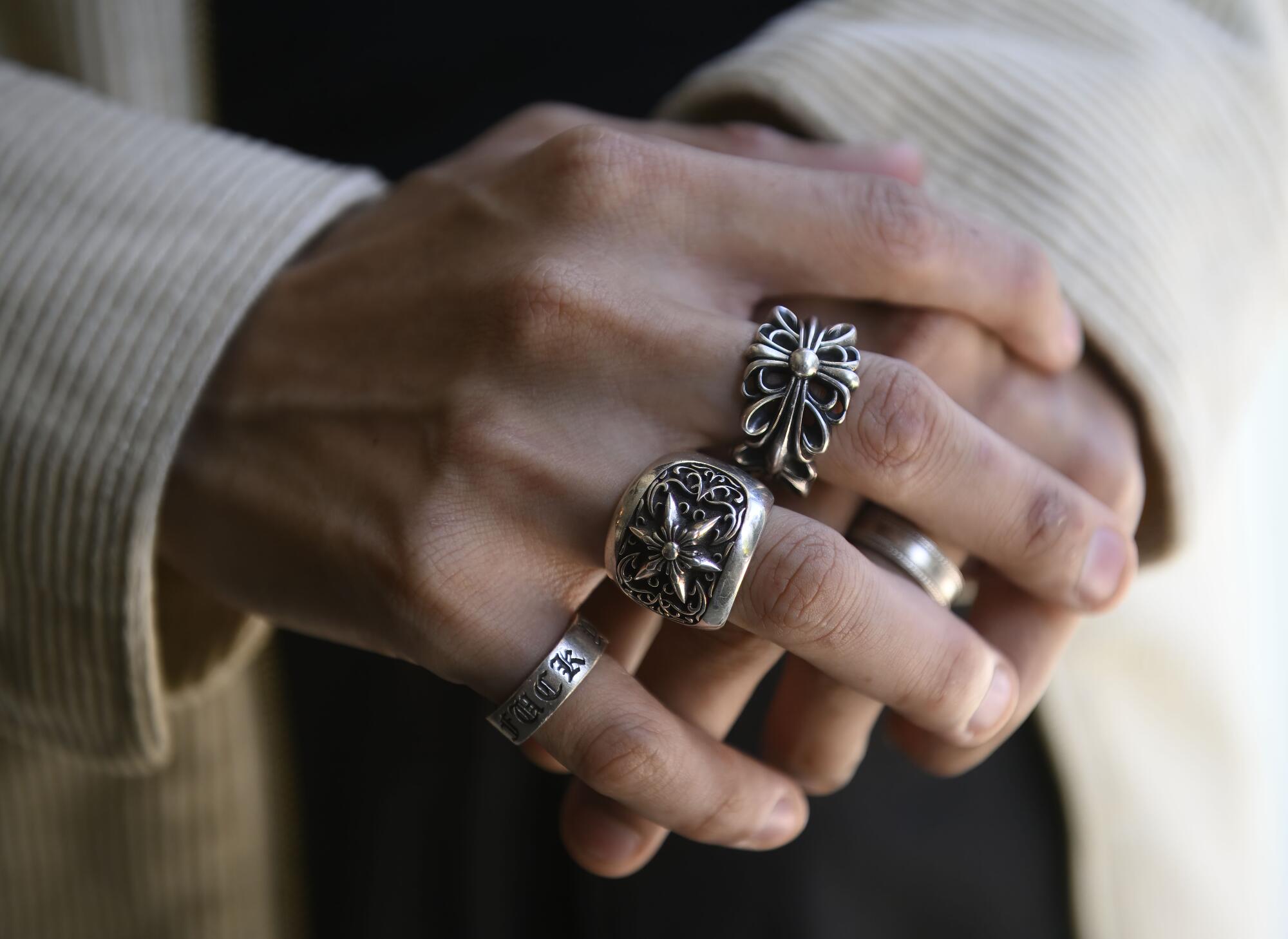 A man wears rings on some of his fingers.
