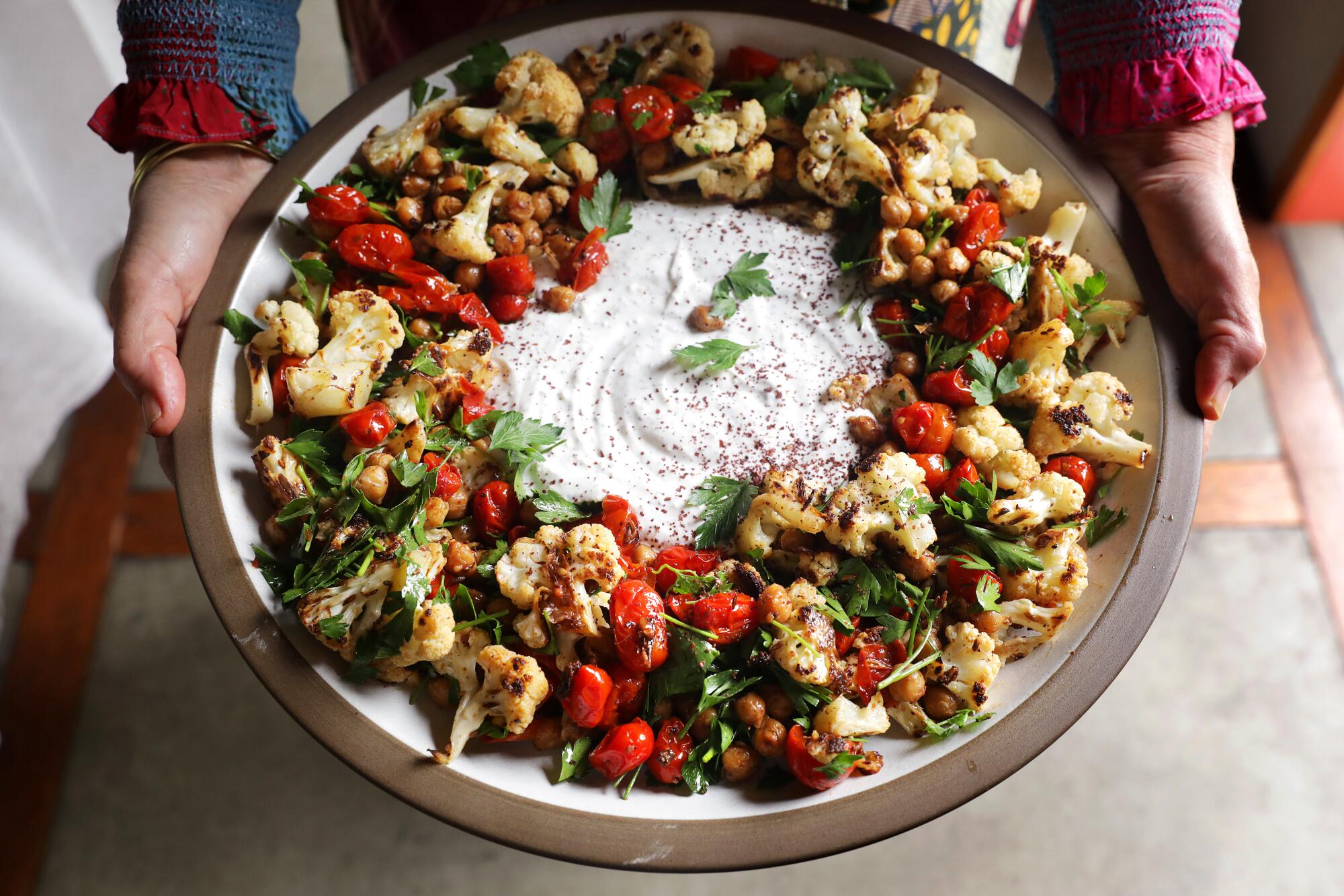 A platter of chickpeas, cauliflower and tomatoes with sumac yogurt in the center