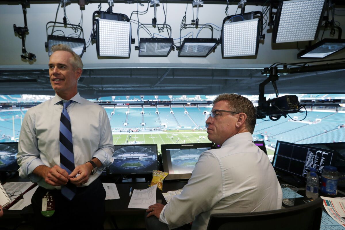 FILE - Fox Sports play-by-play announcer Joe Buck, left, and analyst Troy Aikman work in the broadcast booth before a preseason NFL football game between the Miami Dolphins and Jacksonville Jaguars in Miami Gardens, Fla., Aug. 22, 2019. On Monday, May 16, 2022, Buck and Aikman made their first trips to ESPN headquarters in Bristol, Connecticut, to meet with executives and their future co-workers as preparations for the upcoming season began to ramp up. (AP Photo/Lynne Sladky, File)
