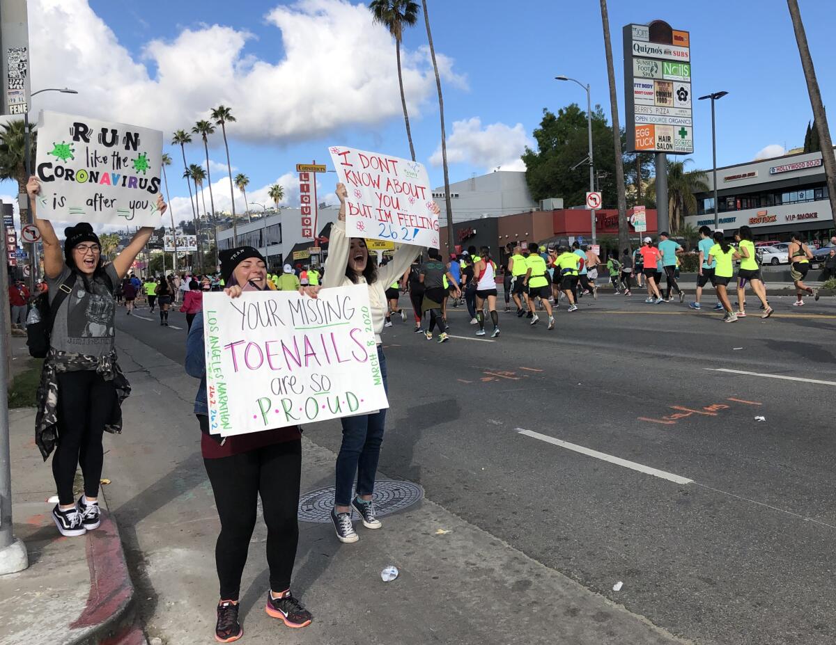 At the L.A. Marathon, a woman holds a sign reading "Run like the coronavirus is after you." 