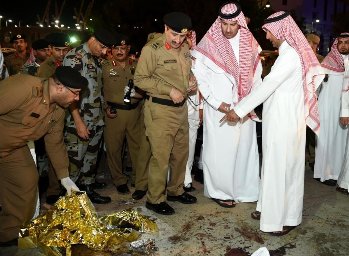 Faisal bin Salman bin Abdulaziz, governor of Medina province, center, and security officers look at blood stains on the ground after a suicide attack near one of Islam's holiest sites, the Prophet's Mosque in Medina, on Monday.