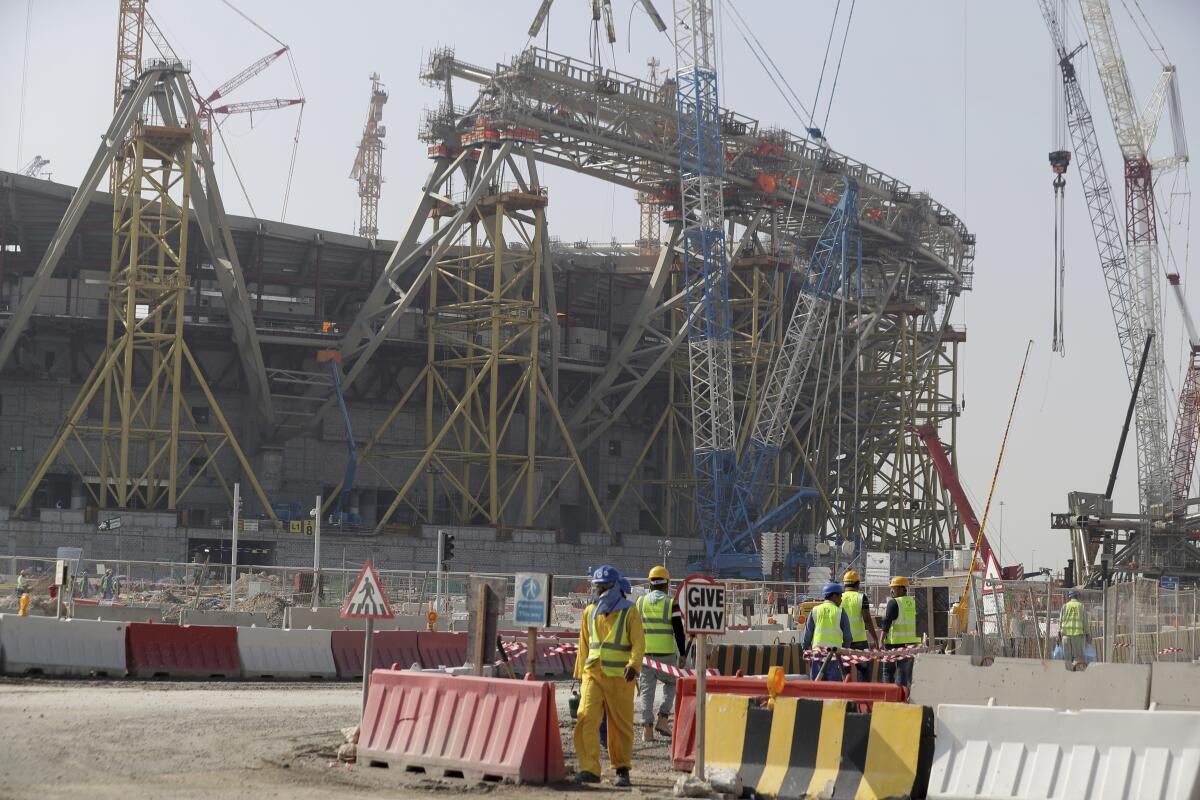 Workers walk to the Lusail Stadium, one of the 2022 World Cup stadiums, 