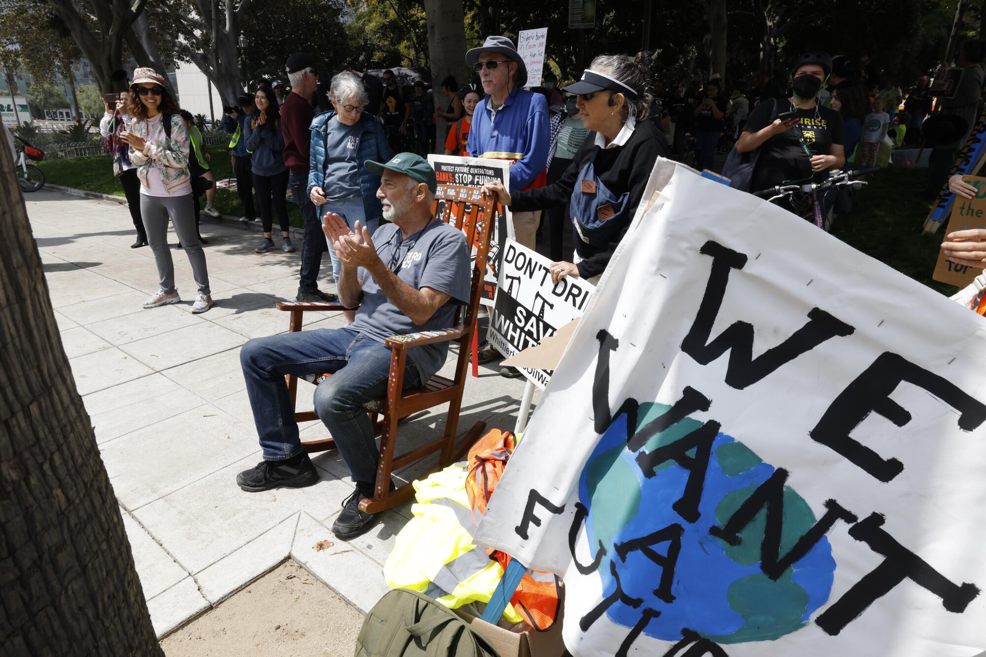 A person sits on a rocking chair near a "We Want A Future" banner.