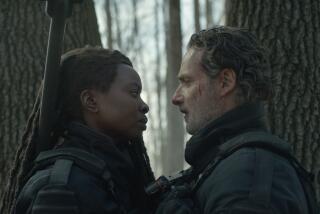 A bloodied man and an armed woman stand face to face in a forest.