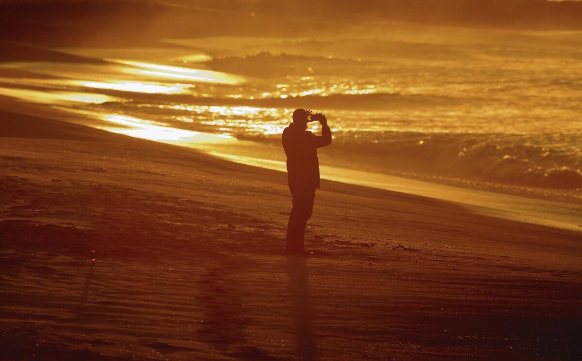 A photographer captures the sunrise at Seal Beach south of the pier on Jan. 21.