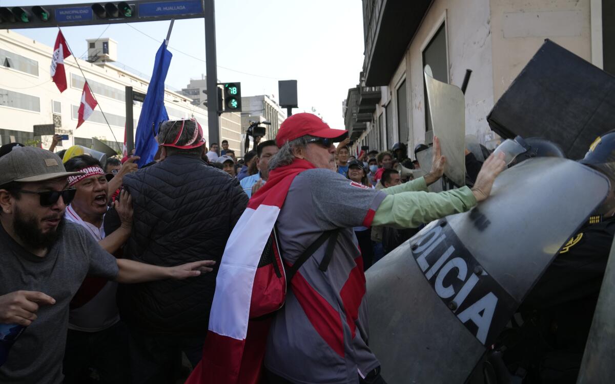 Manifestantes antigubernamentales chocan con la policía antidisturbios cerca del palacio de gobierno en Lima, Perú