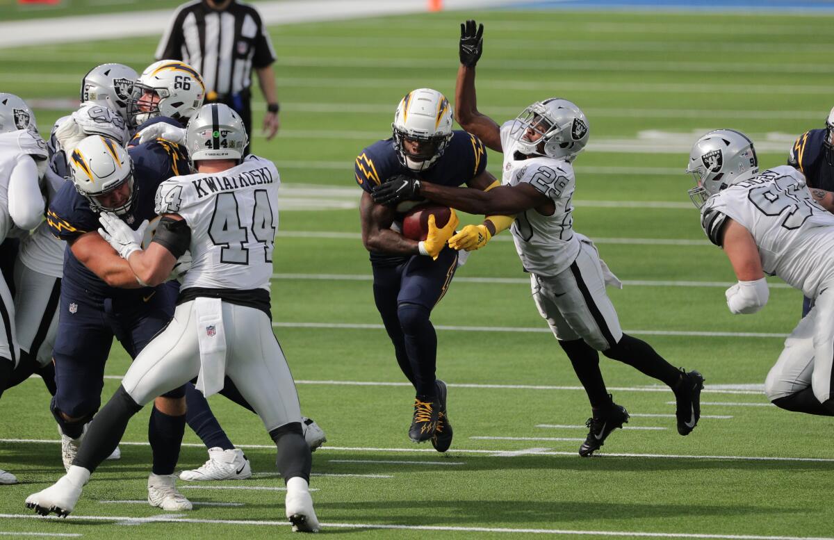 Chargers' Kalen Ballage finds a gap in the Raider defense as free safety Lamarcus Joyner tries to strip the ball.