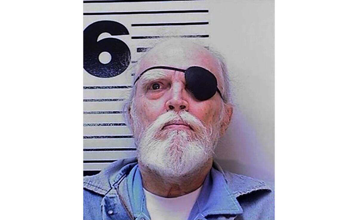 Mugshot of a man with a white beard and wearing an eye patch.
