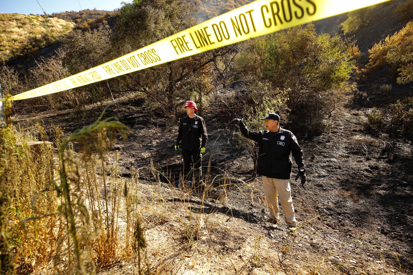 Los Angeles CA. JUNE 10, 2020 - LAFD Arson investigators Robert Williams, left, and Joe Sanchez investigate the origin of the brush fire that broke out after midnight in the Sepulveda Pass threatening homes of Bel Air Wednesday, June 10, 2020. Firefighters were able to stop forward movement of the blaze at about 50 acres. (Al Seib / Los Angeles Times)
