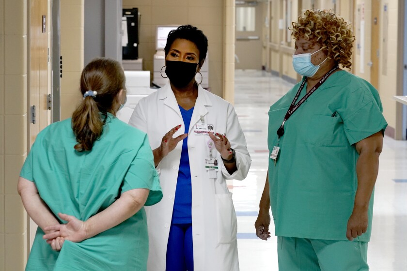 A doctor speaks with two women in scrubs