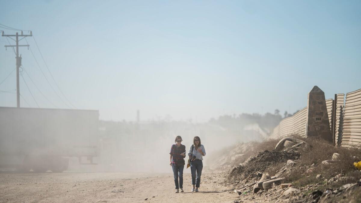 Corine Lensnes and Shanna Yates walk along a dusty road during a tour group organized by artist Christoph Büchel.
