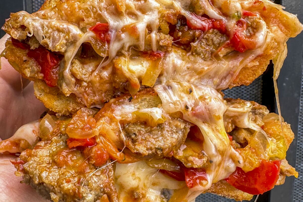 Sausage and peppers sandwich dripping with melted cheese