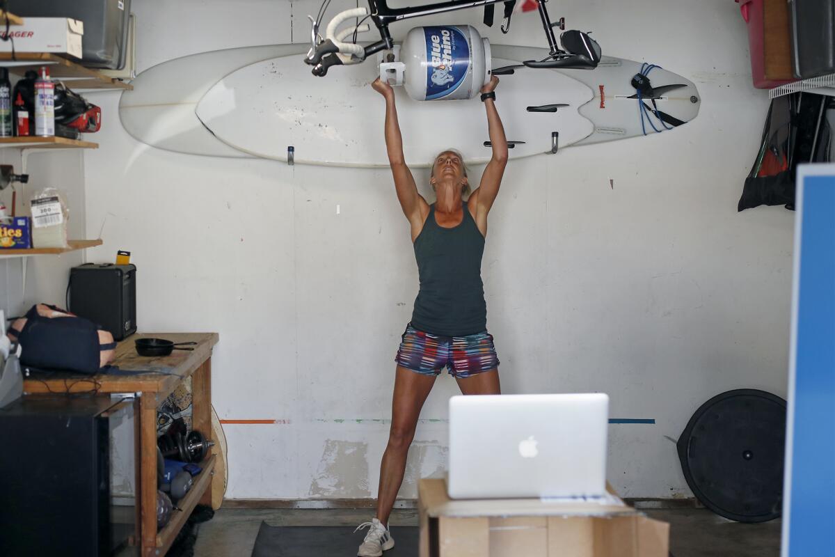 Kelly Evans incorporates a 25-pound propane tank into her exercise routine in her makeshift home studio.