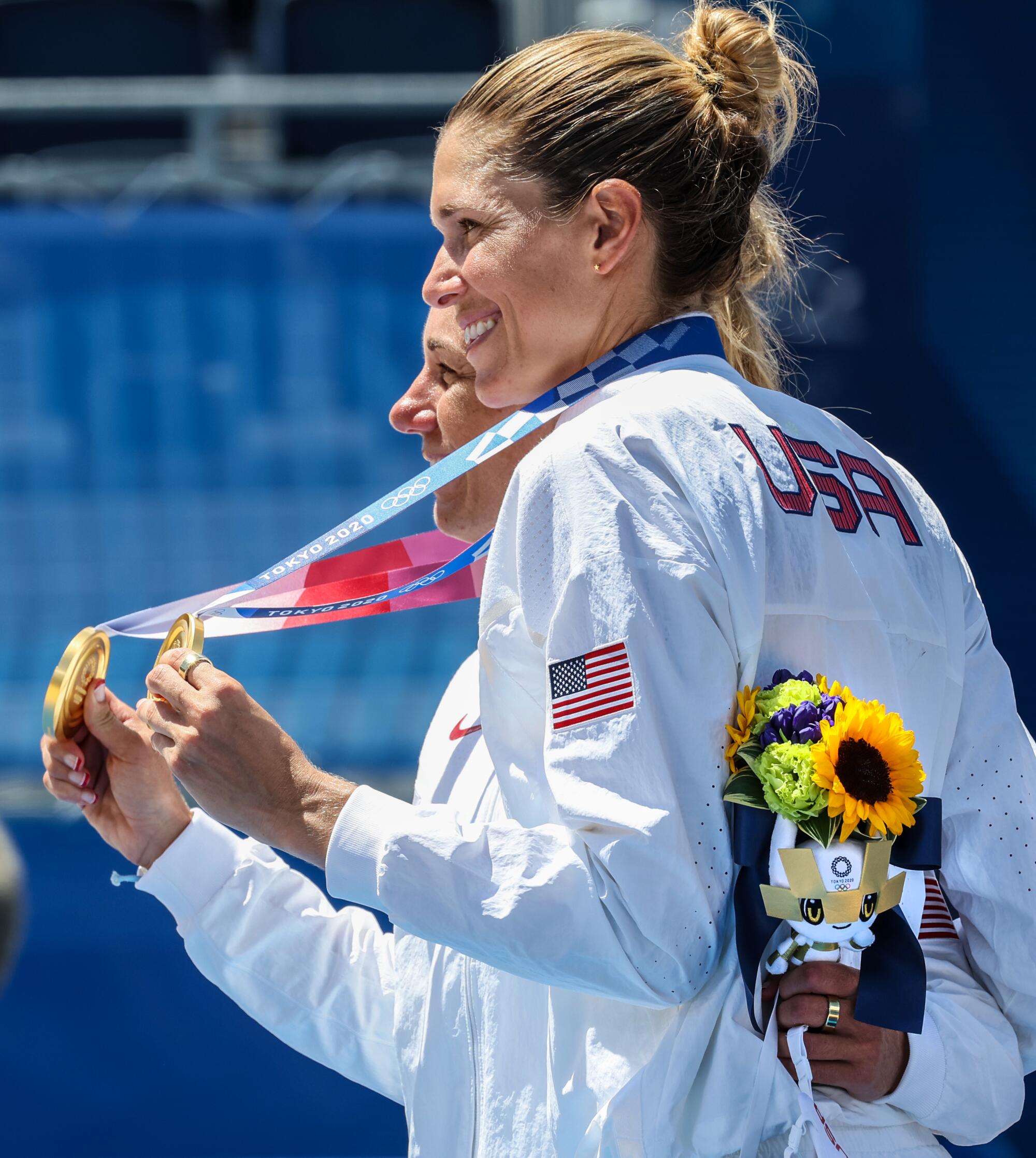 Alix Klineman and April Ross smile and hold up their gold medals