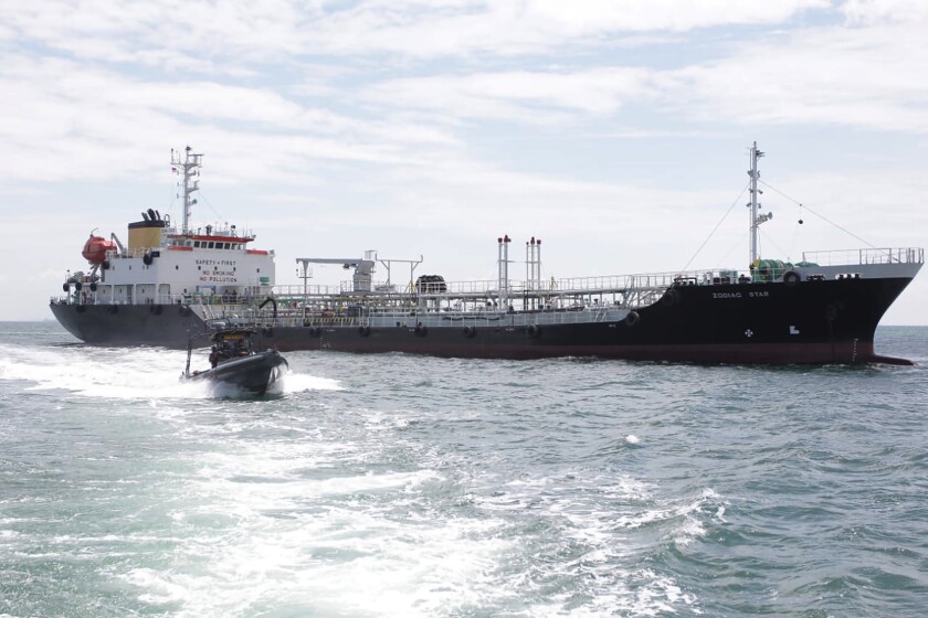 In this undated photo released by Indonesian Navy, a navy boat sails past Panamanian-flagged tanker MT Zodiac Star anchored in Riau Island waters, Indonesia. Indonesian navy seized the massive tanker believed to be loaded with thousands of tons of wasted black oil and has brought the ship to shore for further investigation, officials said Thursday, Sept. 2, 2021.(Indonesian Navy via AP)