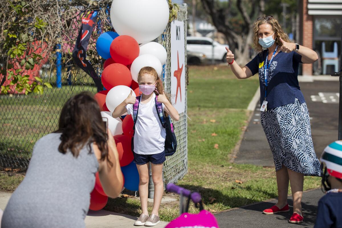 Danielle Hodge, left, takes a picture of her daughter, Isla, 6, and her first-grade teacher, Shari Gaeta.