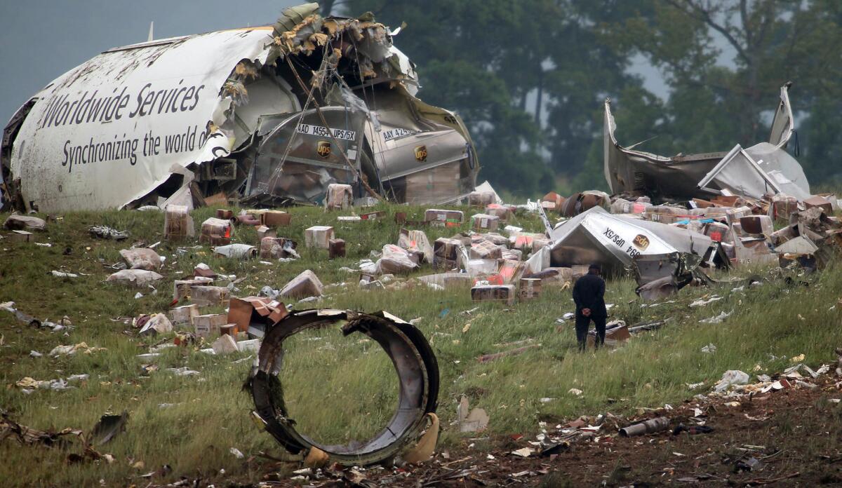 An investigator looks through debris of a UPS A300 cargo plane after it crashed on approach at Birmingham-Shuttlesworth International Airport in Birmingham, Ala.