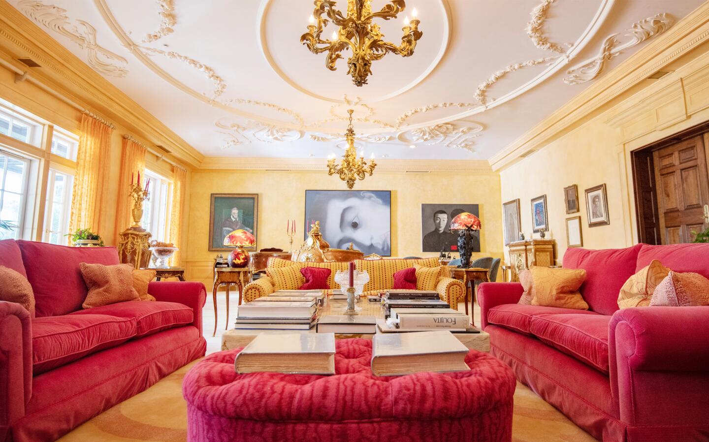 Two gilt chandeliers hang from the elaborate living room ceiling.