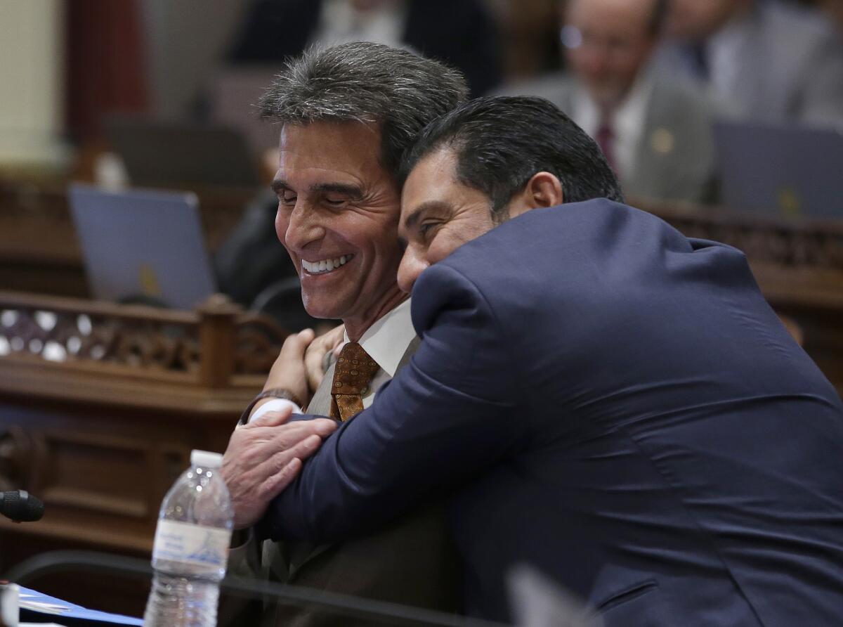 State Sen. Mark Leno (D-San Francisco) left, one of the authors of a bill to raise California's minimum wage, is hugged by Sen. Ben Hueso (D-San Diego) during the Senate vote on the bill.