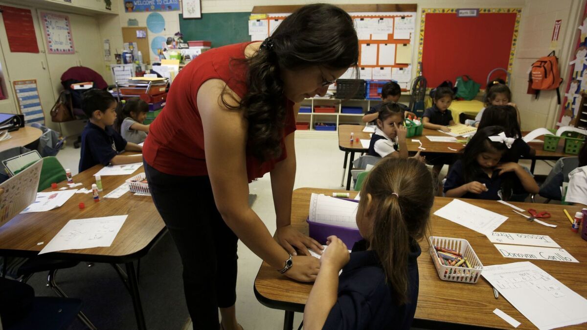 Kindergarten teacher Claudia Garcia helps Michelle Lopez at a Magnolia charter school in Northridge in 2014.