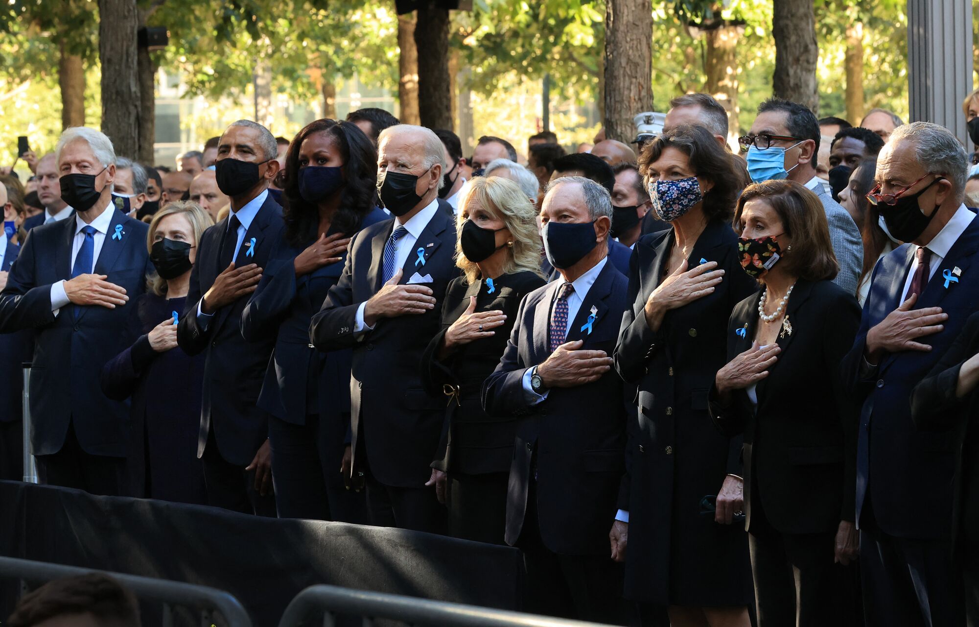 Current and former politcal leaders place their hands on their hearts and stand for the national anthem in New York City.