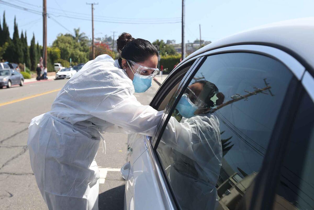 Janet Muratalla administers a drive-up coronavirus swab test outside the Caduceus Medical Group office in Laguna Beach.