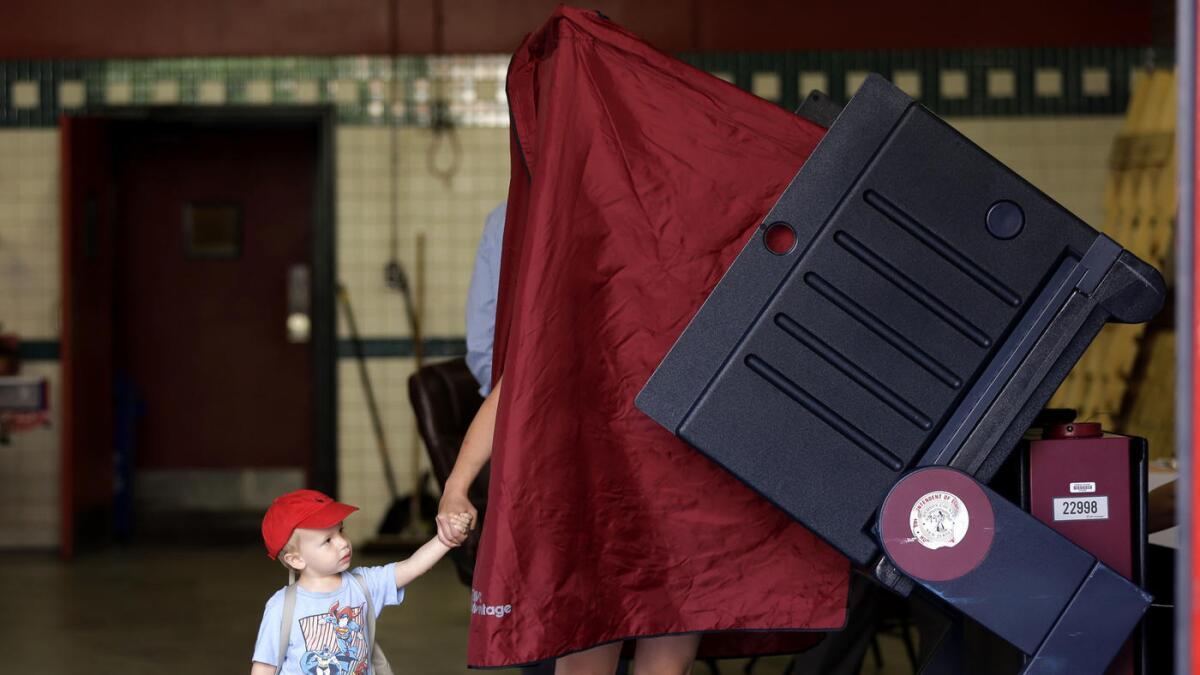 James Percella, de 2 años de edad, toma la mano de su madre mientras ella ingresa a una cabina de votación, en Hoboken, Nueva Jersey, el 7 de junio pasado.