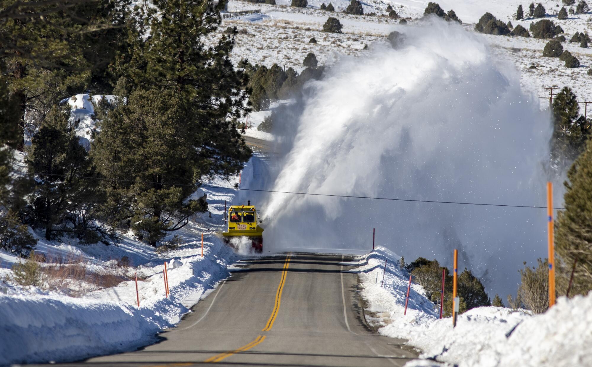 A large plume of snow behind a road plow