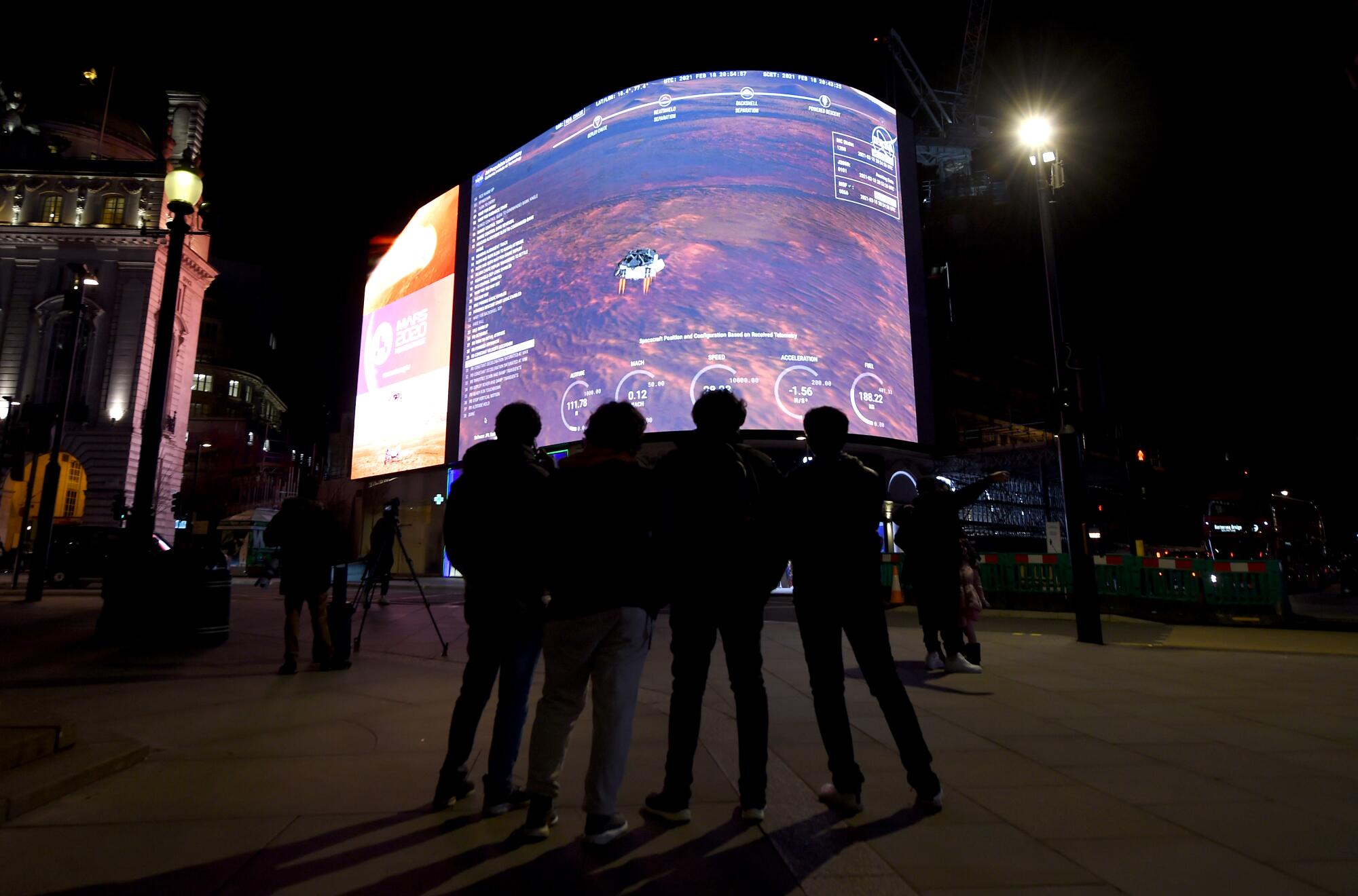 A massive outdoor screen shows a livestream of Mars rover landing