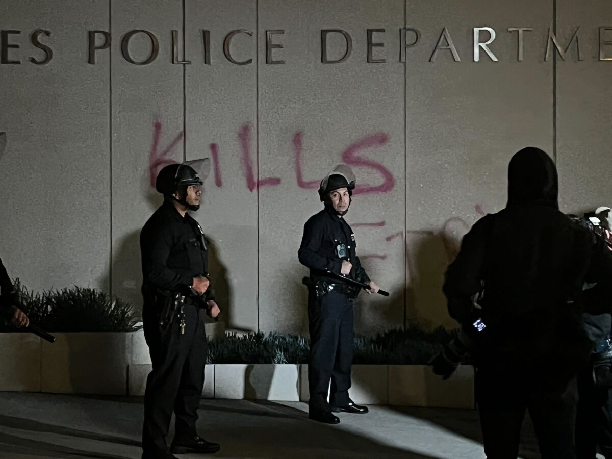 Policiers devant le mot "tue" peint à la bombe sous le "Département de police de Los Angeles" pancarte