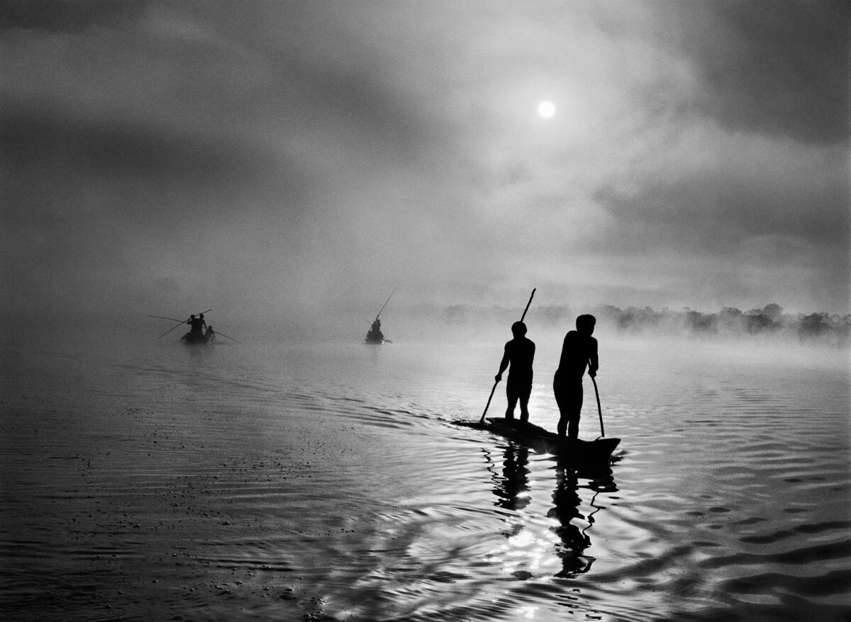At daybreak, Waura tribesmen travel by canoe to collect the "waiting net" that caught fish overnight. 