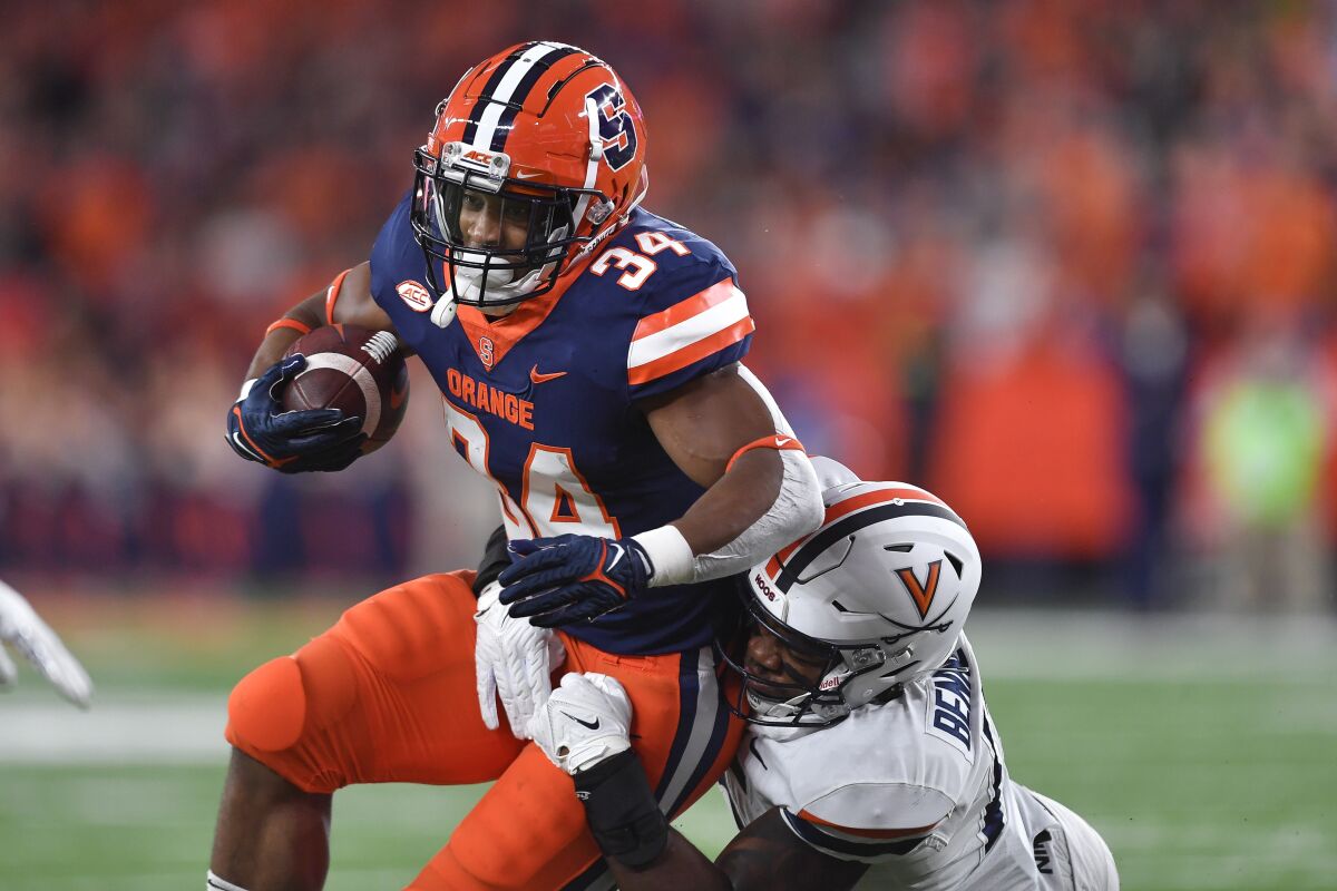 Syracuse running back Sean Tucker (34) is tackled by Virginia linebacker Chico Bennett Jr. (15) during the first half of an NCAA college football game Friday, Sept. 23, 2022, in Syracuse, N.Y. (AP Photo/Adrian Kraus)