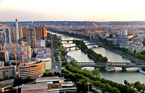 A view from the Eiffel Tower of Paris and the Seine River on a summer evening.