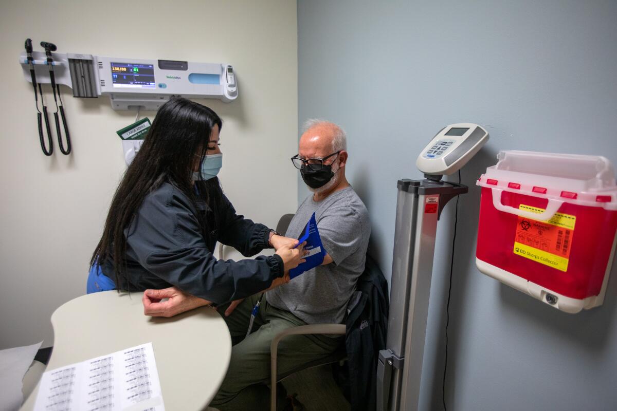 A nurse checks a man's blood pressure in a doctor's office.