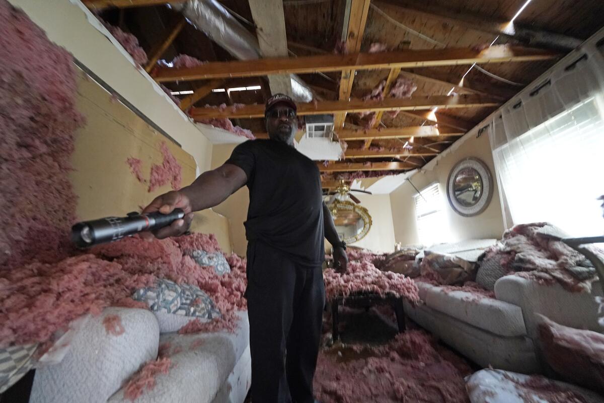 FILE - In this Sept. 7, 2021 file photo, Michael Lathers shows the insulation and collapsed ceiling in his flooded home, in the aftermath of Hurricane Ida in LaPlace, La. Destruction caused by Hurricane Ida has people in south Louisiana debating whether they want to relocate — and where they might go. (AP Photo/Gerald Herbert, File)