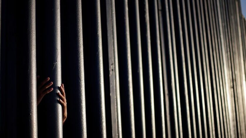 In this June 13, 2013 photo, Daniel Zambrano, of Tijuana, Mexico, holds one of the bars that make up the border wall separating the U.S. and Mexico where the border meets the Pacific Ocean in San Diego.