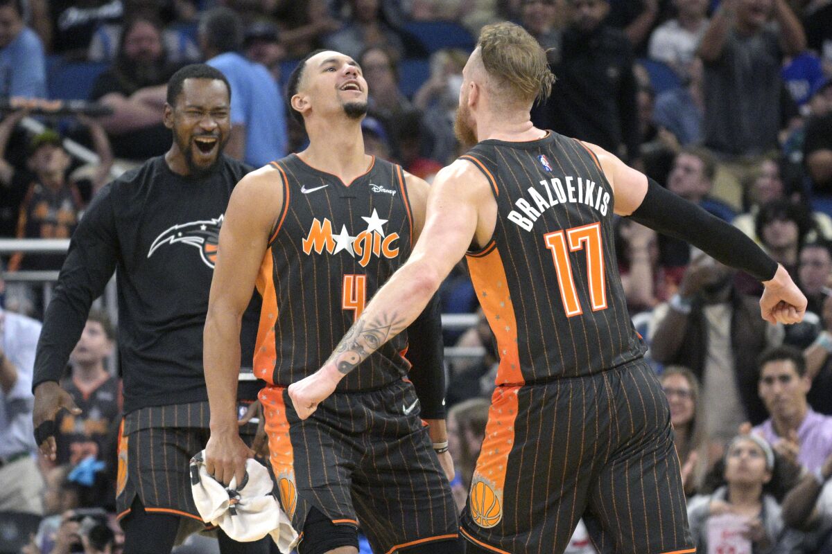 Orlando Magic forward Ignas Brazdeikis (17) celebrates with guard Jalen Suggs (4) and guard Terrence Ross, left, after Brazdeikis scored late in the second half of an NBA basketball game against the Cleveland Cavaliers, Tuesday, April 5, 2022, in Orlando, Fla. (AP Photo/Phelan M. Ebenhack)