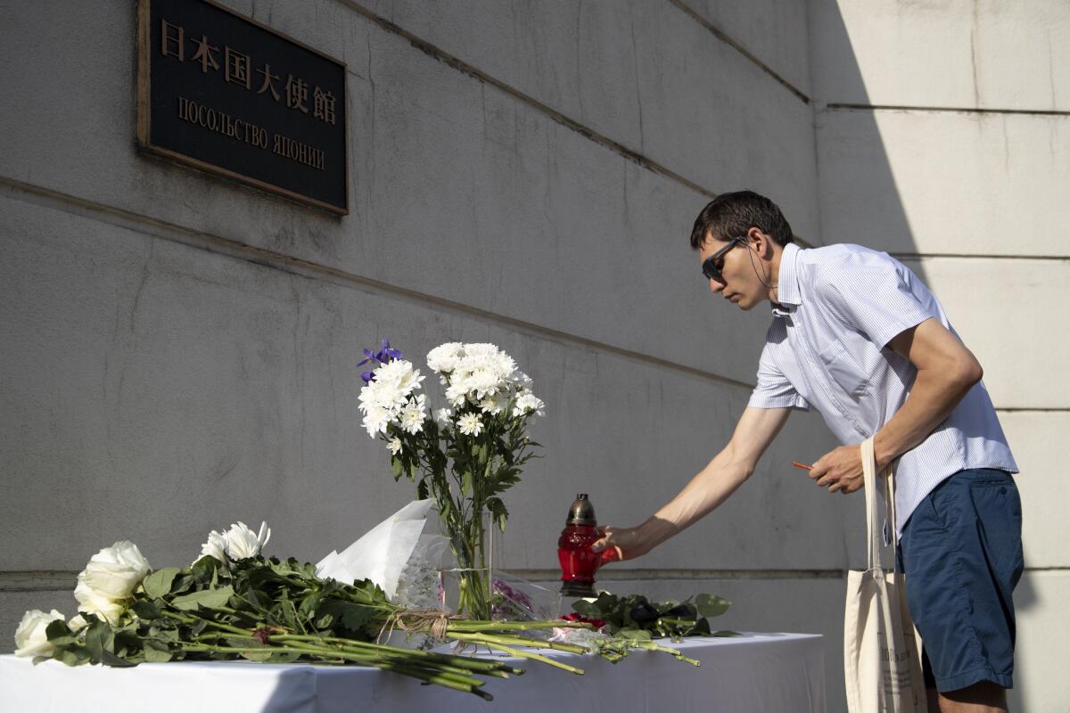 A man puts a candle in front of the entrance of the Japanese embassy in memory of the former Prime Minister Shinzo Abe.