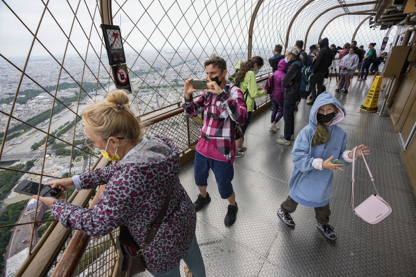 People hold their phones as they take pictures of the expansive view from behind a wire grate.