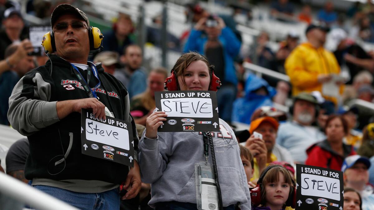 Fans hold up signs supporting broadcaster Steve Byrnes during the April 19 NASCAR Sprint Cup Series race at Tennessee's Bristol Motor Speedway.