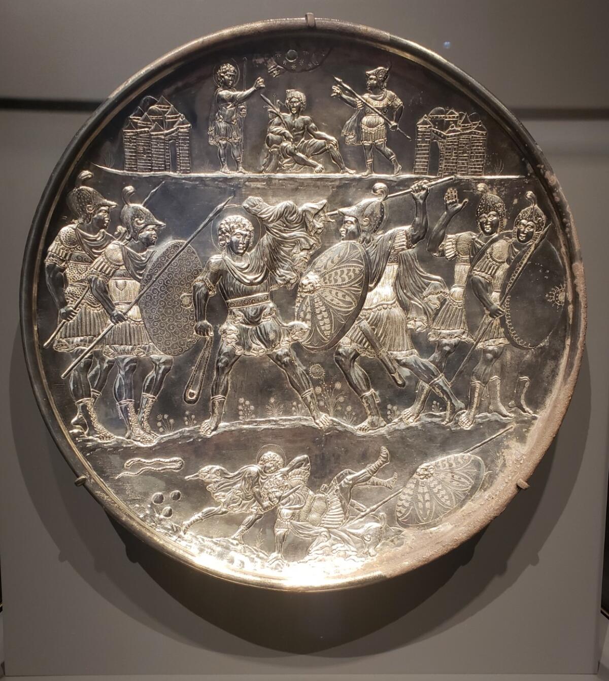 A silver plate shows men fighting.