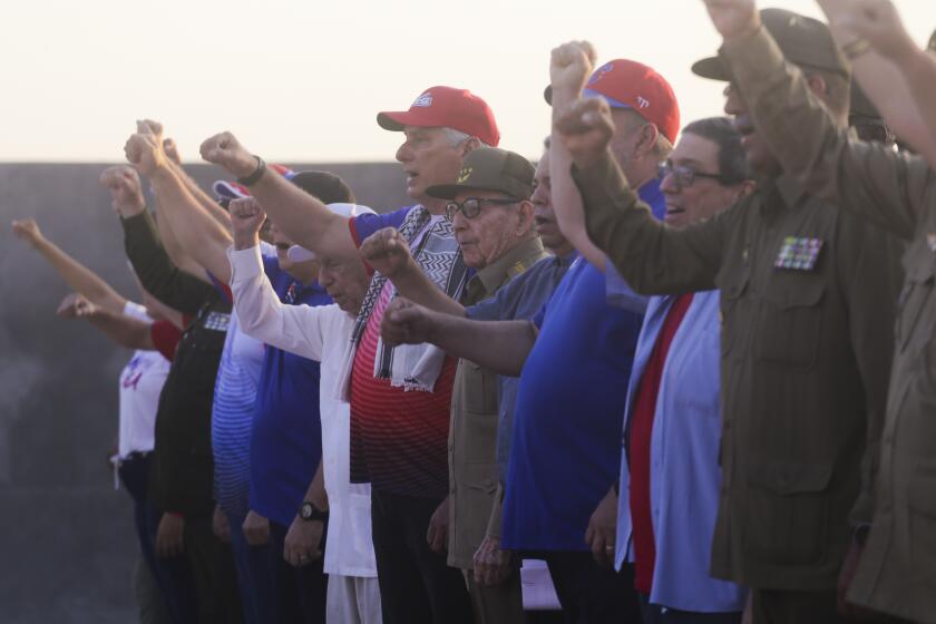 El presidente cubano Miguel Díaz-Canel, centro izquierda con un sombrero rojo, y el expresidente Raúl Castro asisten a una reunión para conmemorar el Día Internacional de los Trabajadores en la Plaza Antiimperialista José Martí en La Habana, Cuba, el miércoles 1 de mayo de 2024. (AP Foto/Ariel Ley)