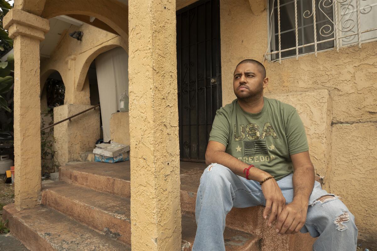Dennys Rene Rivas Williams sits on steps outside his home.