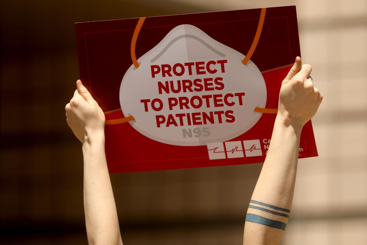 Two arms hold up a sign saying "protect nurses to protect patients"
