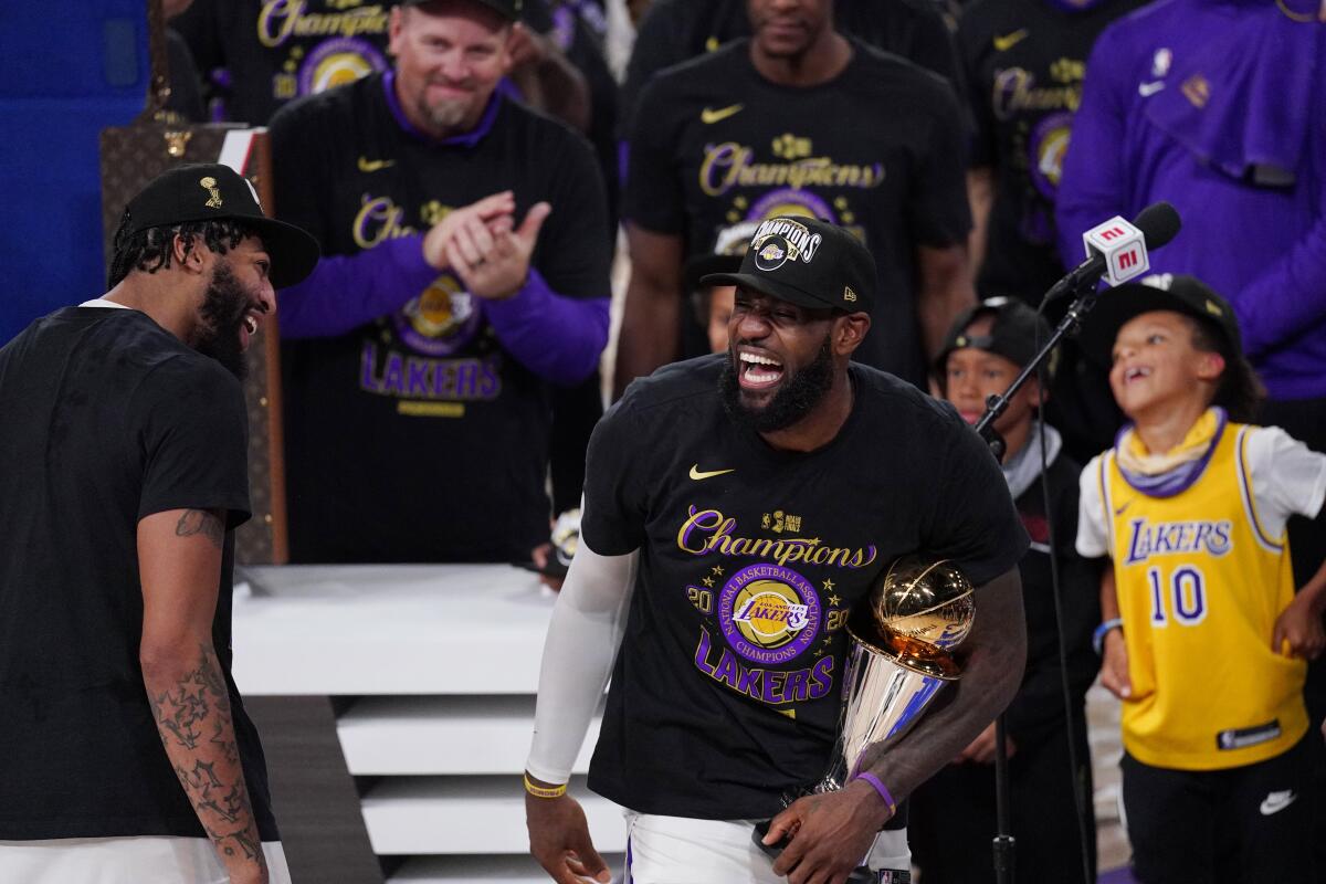 Lakers' LeBron James holds the MVP trophy as he celebrates with Anthony Davis and teammates.