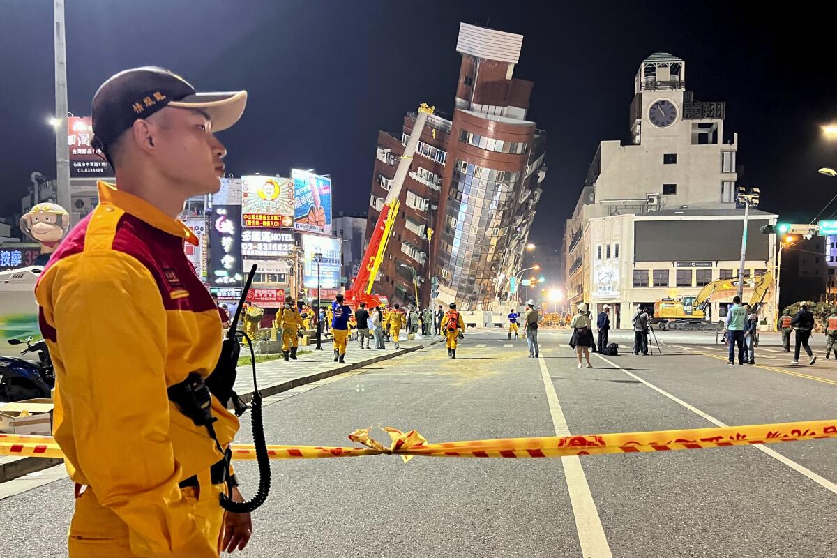 A rescue worker stands near the cordoned-off site of a leaning building in Hualien, Taiwan.